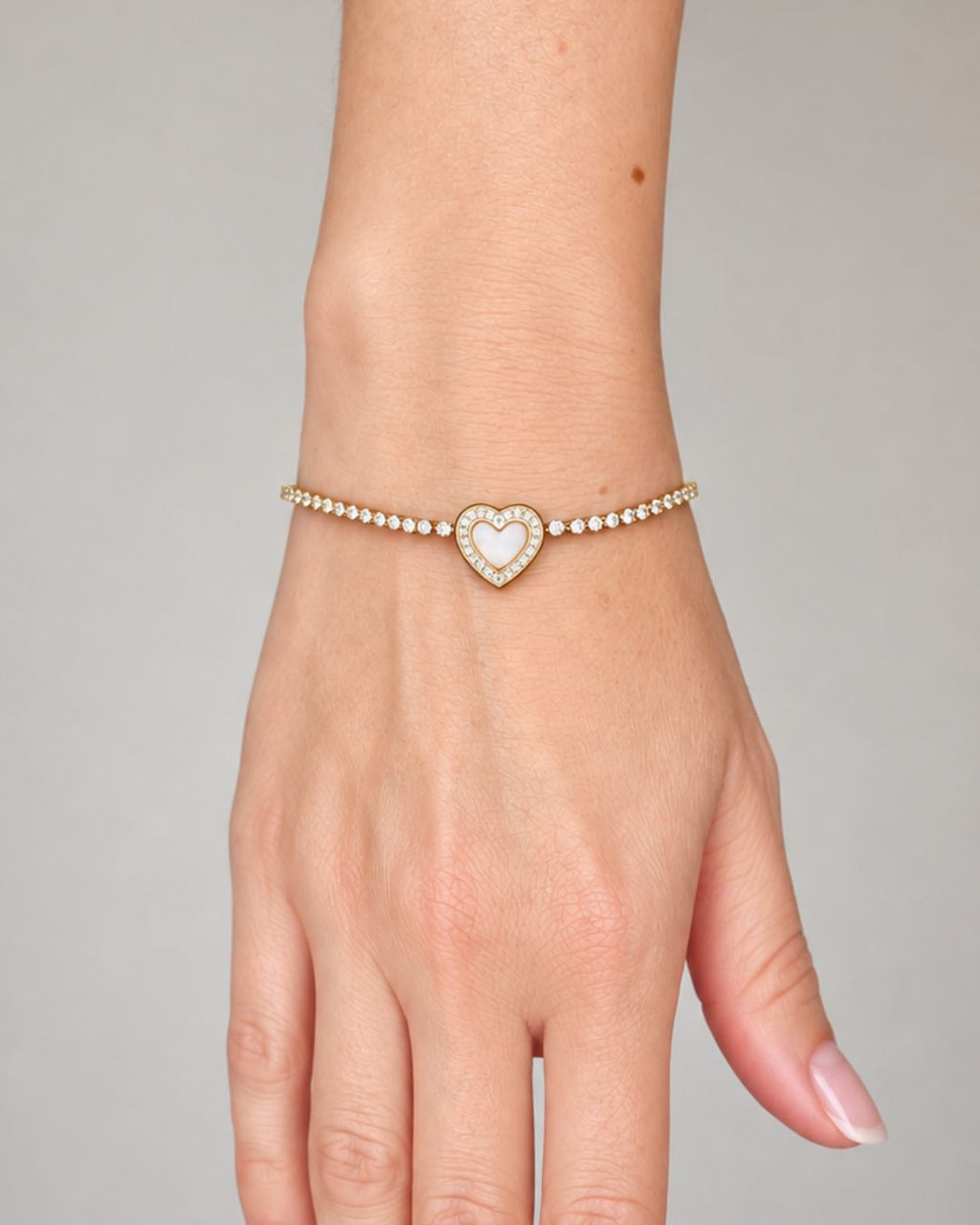 Close-up of a woman's wrist wearing the Eternal Heart gold PVD bracelet, featuring a delicate crystal tennis chain and an elegant heart centerpiece.