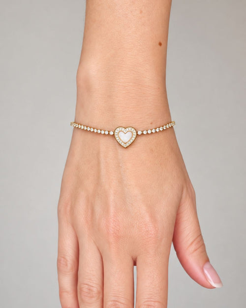 Close-up of a woman's wrist wearing the Eternal Heart gold PVD bracelet, featuring a delicate crystal tennis chain and an elegant heart centerpiece.