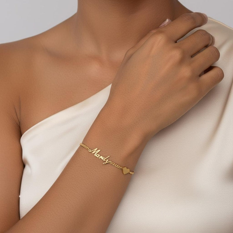 Woman wearing the gold-finish Fidji Love personalised heart bracelet with a white outfit.