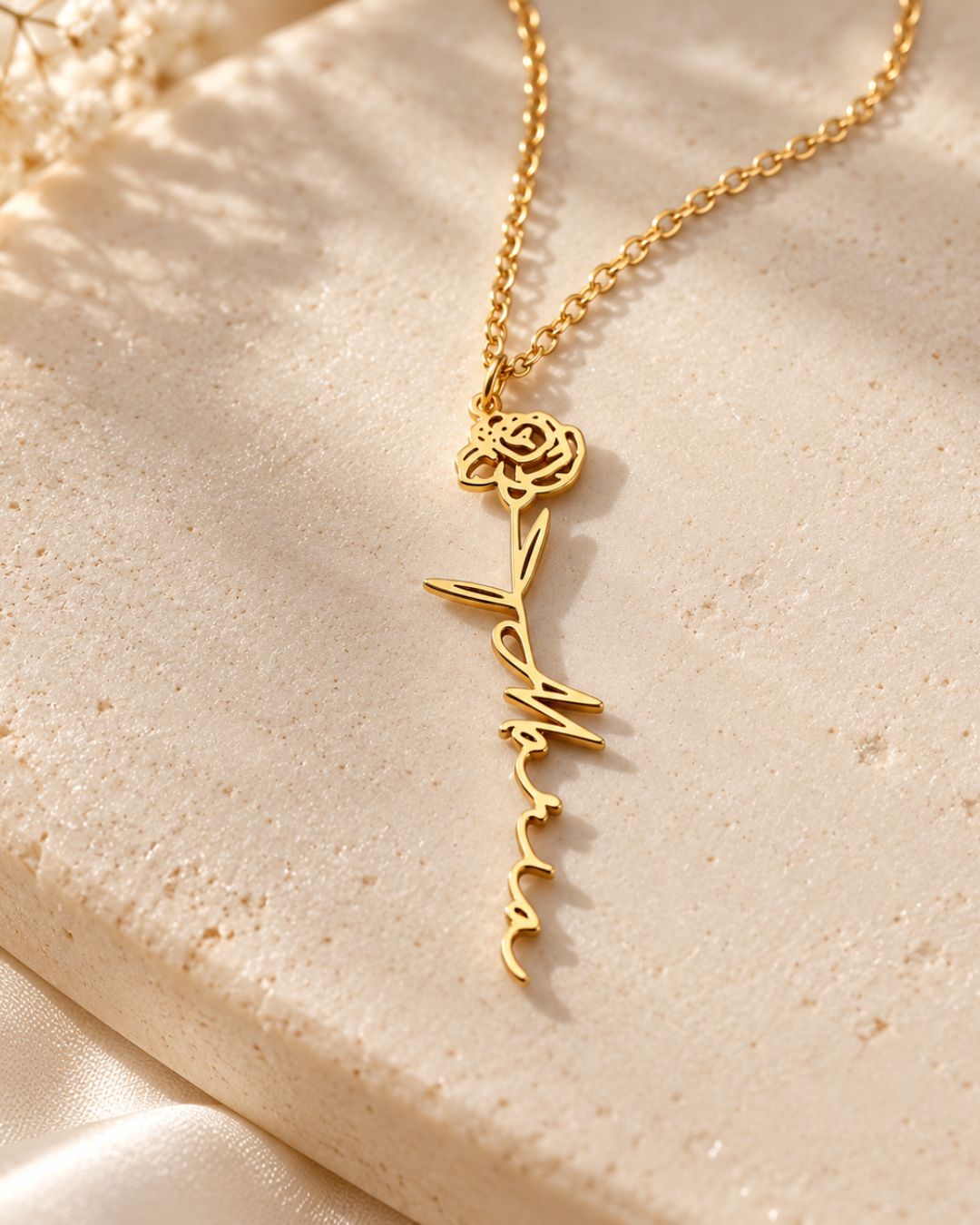 GIVERNY gold-tone necklace with a birth flower and personalised script name displayed on a beige surface