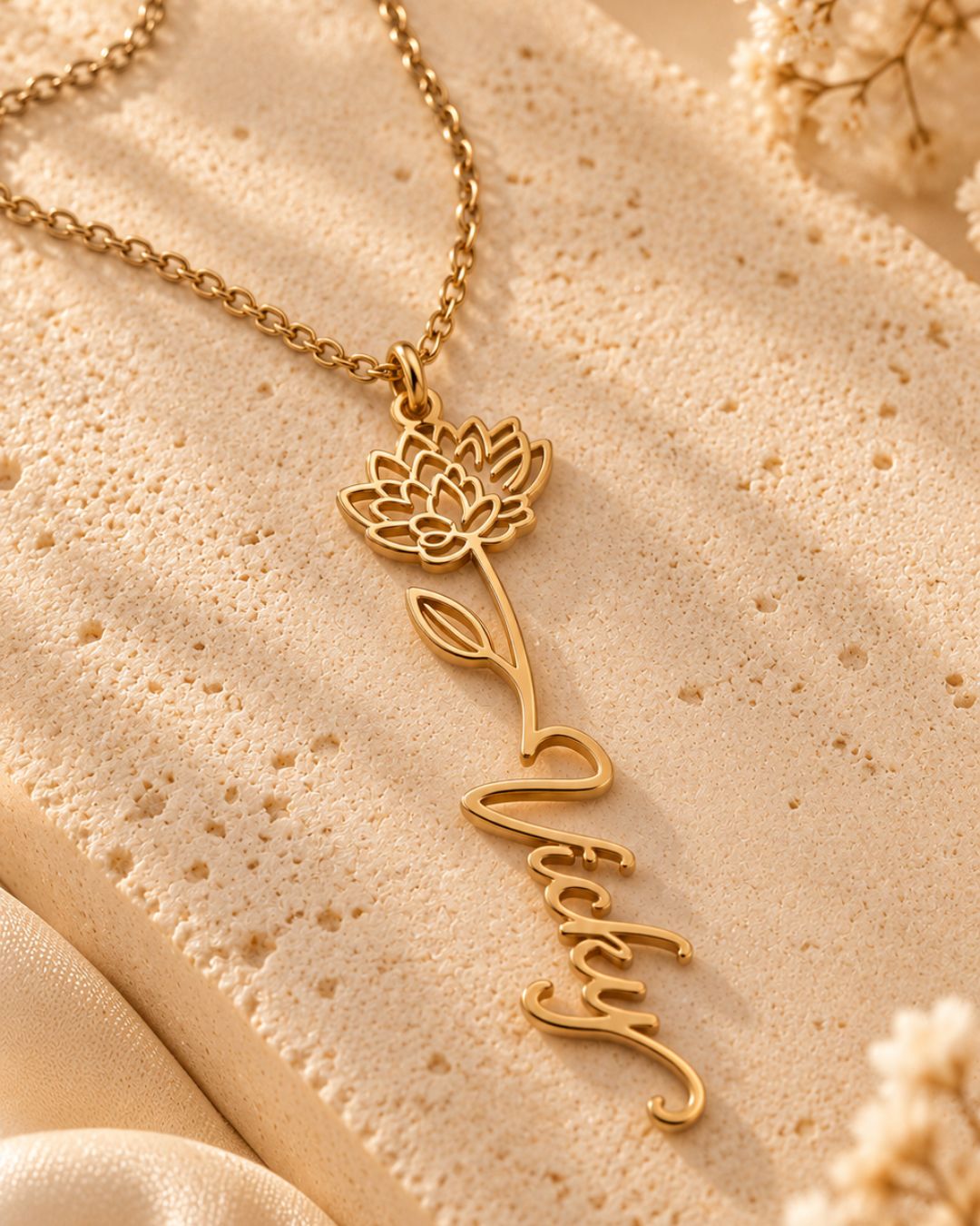 GIVERNY gold-tone birth flower necklace with the name Vicky displayed on a textured beige surface