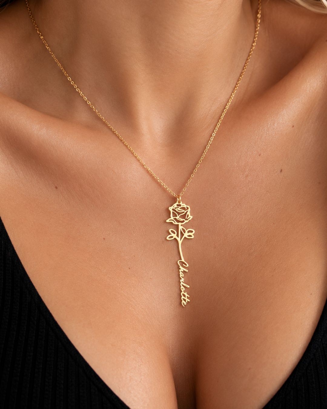 Close-up of a woman wearing a GIVERNY gold-tone personalised birth flower necklace with a black neckline