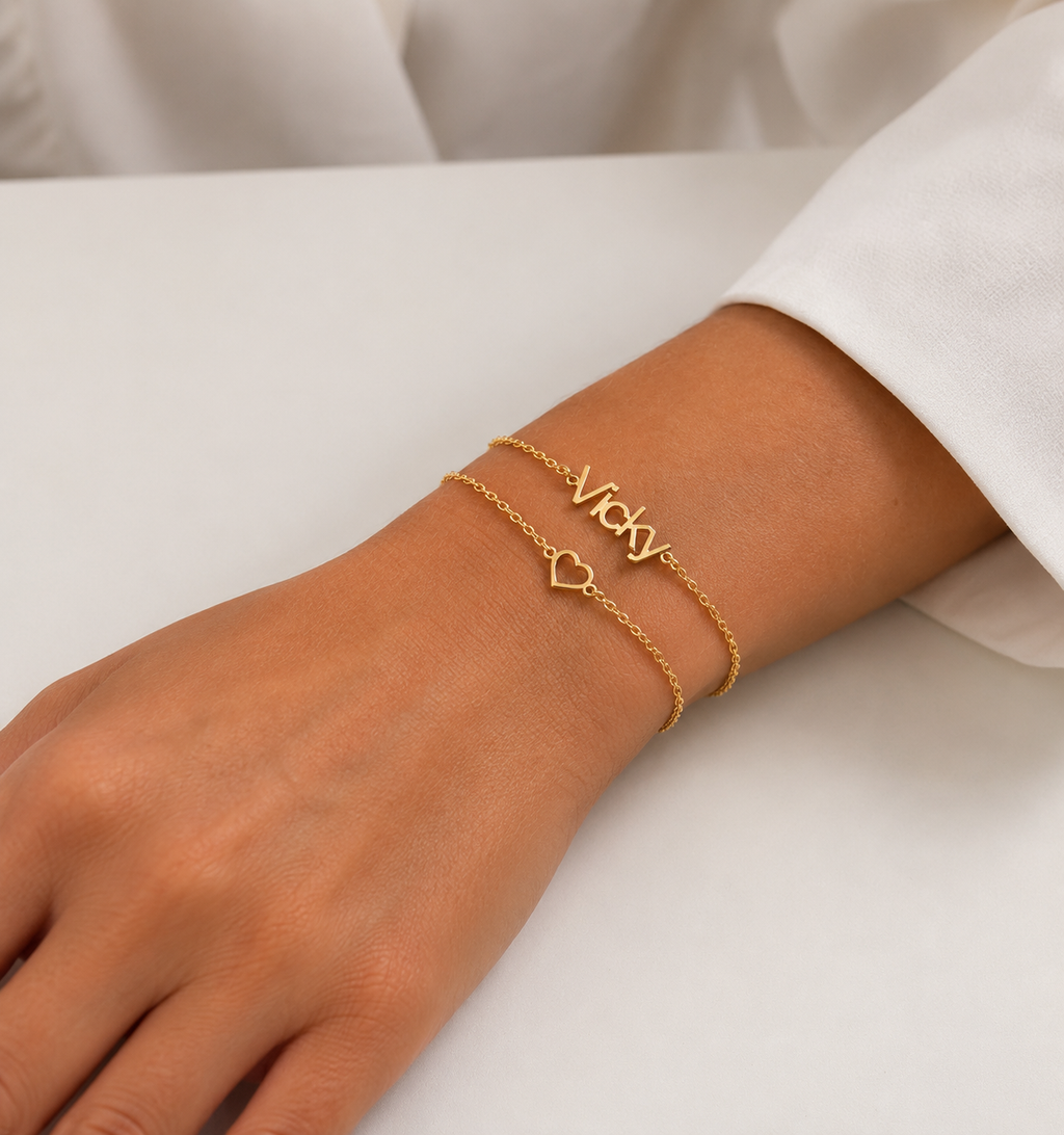 Gold-finish Hope personalised double chain heart bracelet worn on a wrist beside a white sleeve.