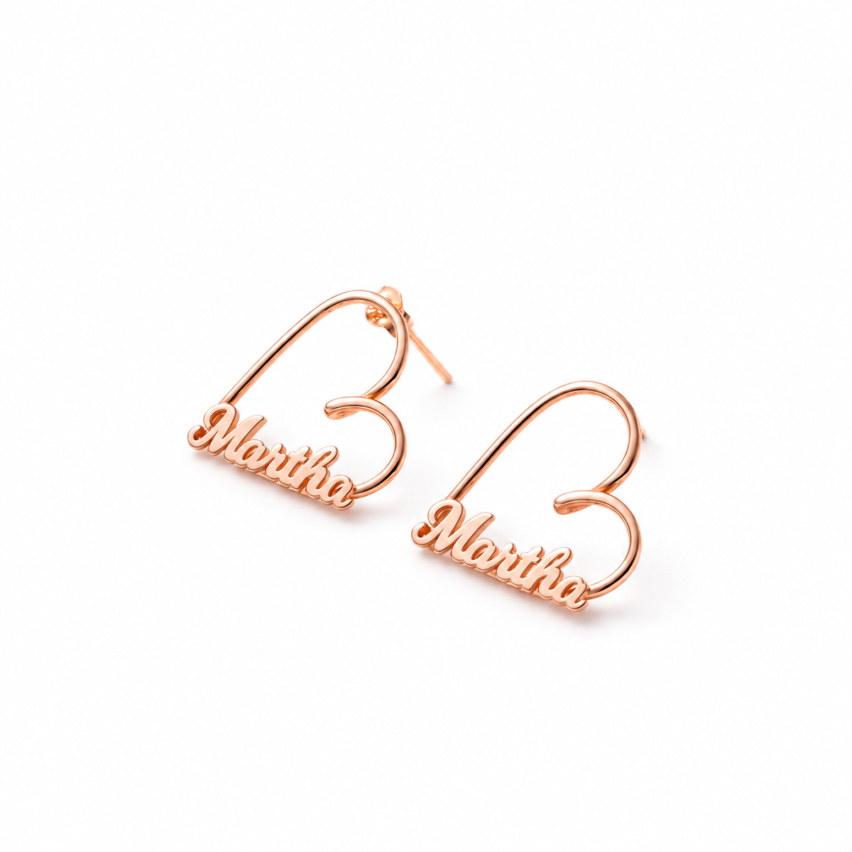 Rose gold-finish Love Story personalised heart earrings with “Martha” lettering on a white background.