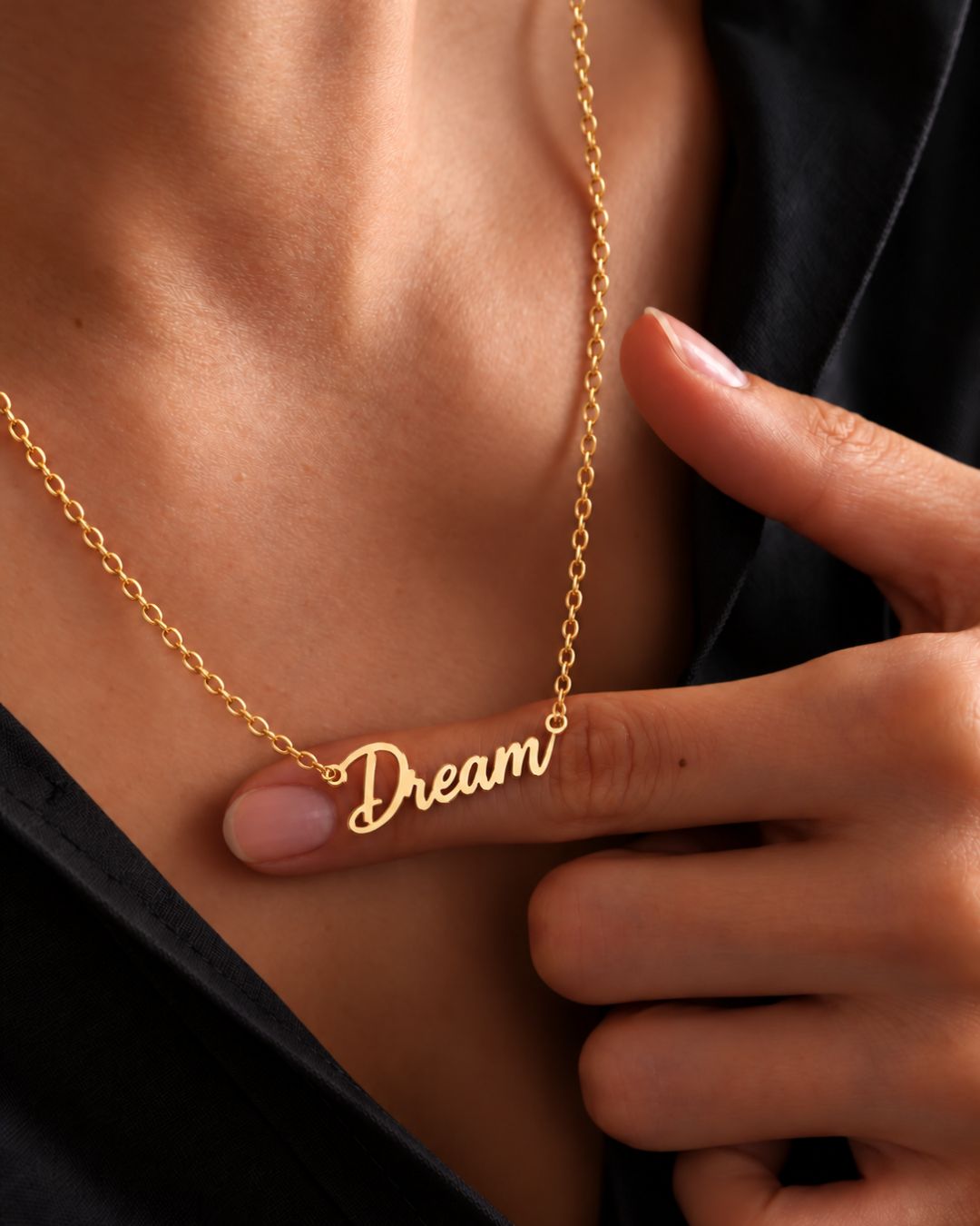 Close-up of the MIAMI gold-tone Dream necklace held against a woman's finger