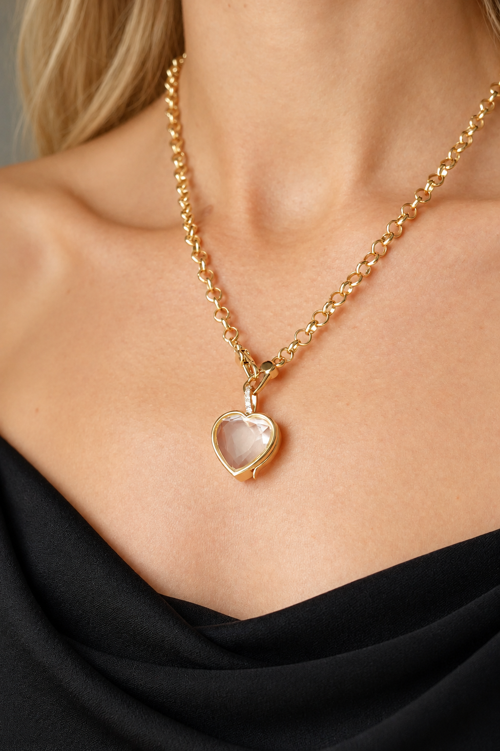 Woman wearing a gold heart locket necklace with an elegant black top.