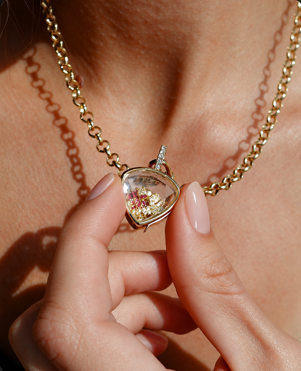 Close-up of a woman holding a gold heart locket necklace filled with personalised charms.