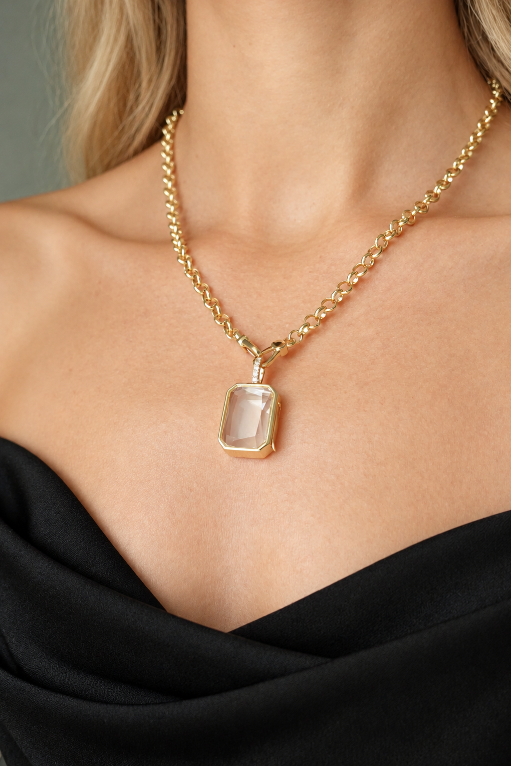 Woman wearing a gold rectangular locket necklace with a black outfit.