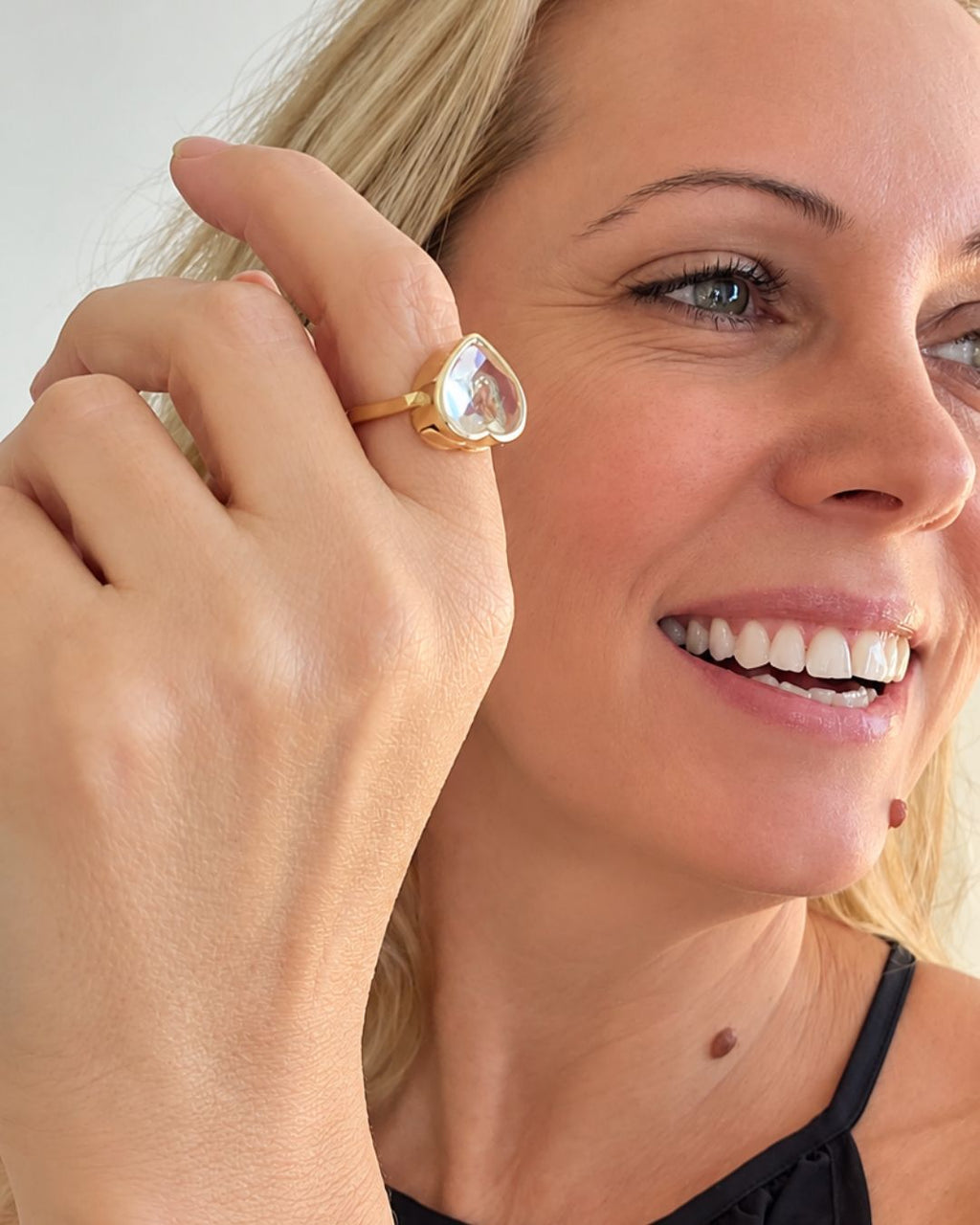Femme souriante portant une bague Remember Ring dorée en forme de cœur
