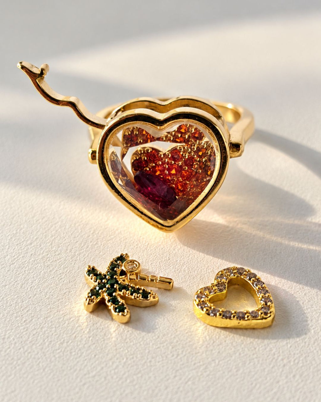 Gros plan du cœur transparent doré de la Remember Ring contenant des charms rouges, avec deux charms posés à côté.