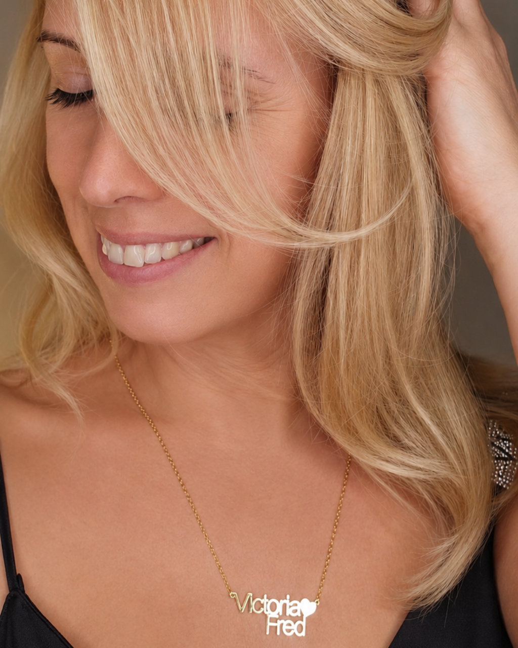 Woman wearing the Together personalised heart name necklace, featuring two lines of lettering and a heart detail.