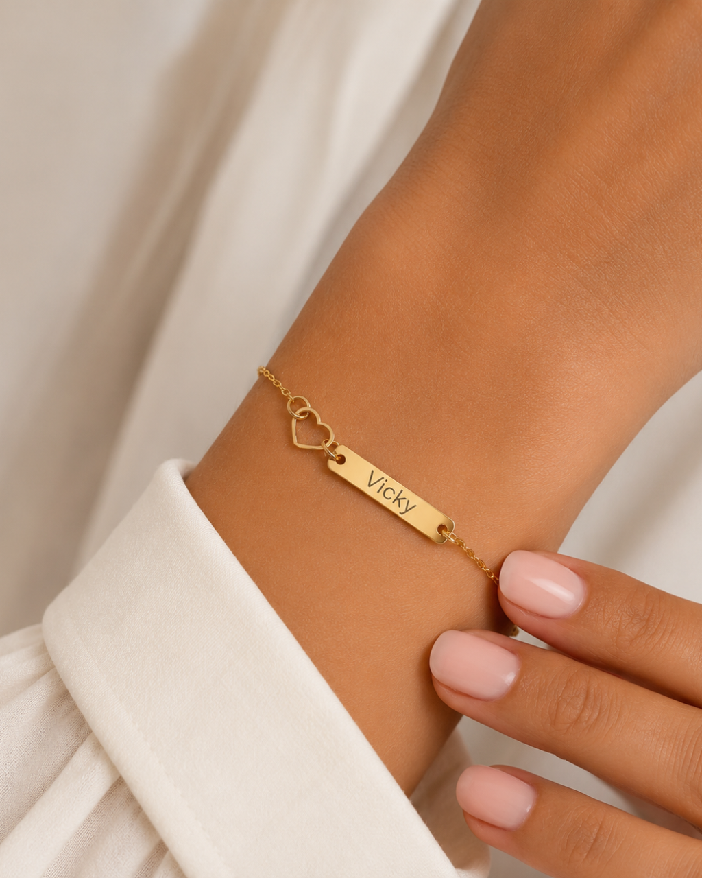 Gold-finish Venice Heart Bar Bracelet worn on a wrist beside a white sleeve, showing its engraved bar and open-heart detail.